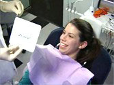 Photo of happy patient admiring her teeth whitening results in a mirror following her treatment.