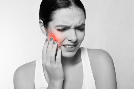 Woman holding her jaw in pain. 